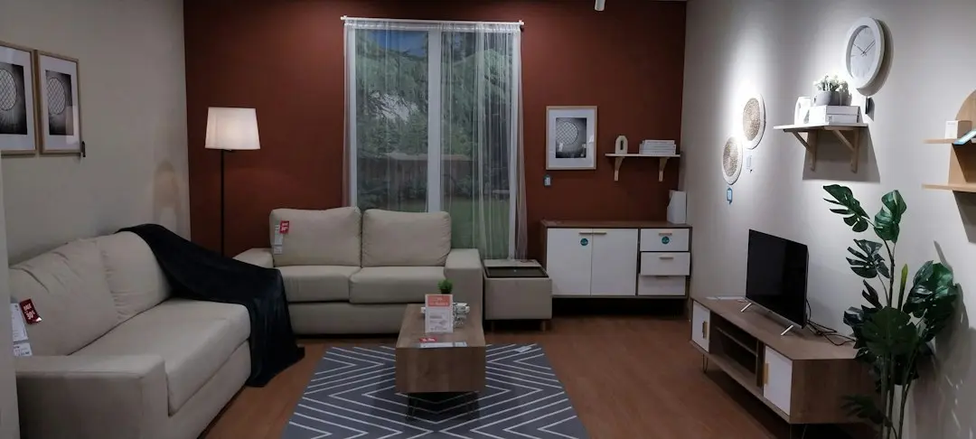 A living room with a beige sofa, a floor lamp and a TV on a low cabinet, the kind of home where Nartiel8k IPTV is watched
