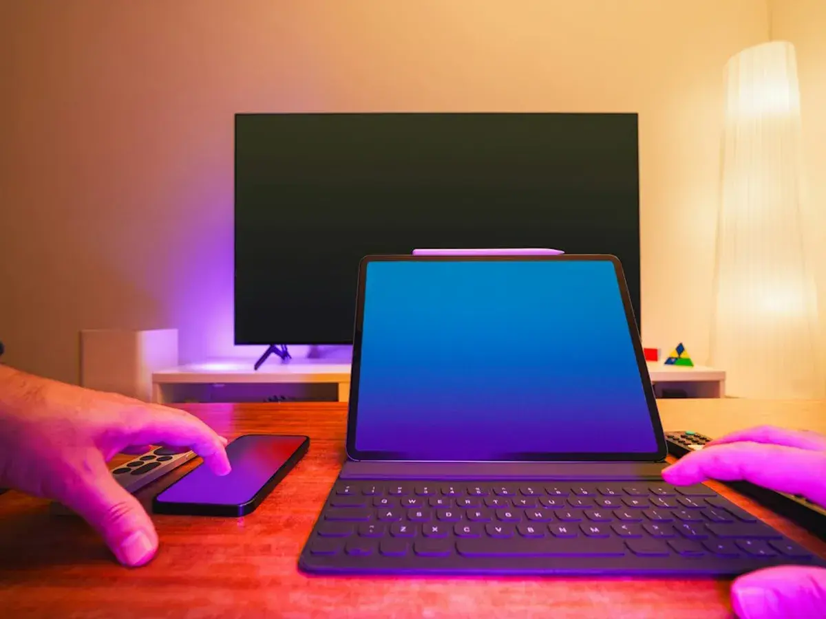 A tablet, a smartphone and a remote on a desk in front of a flat-screen TV, ready to test a Nartiel8k free trial